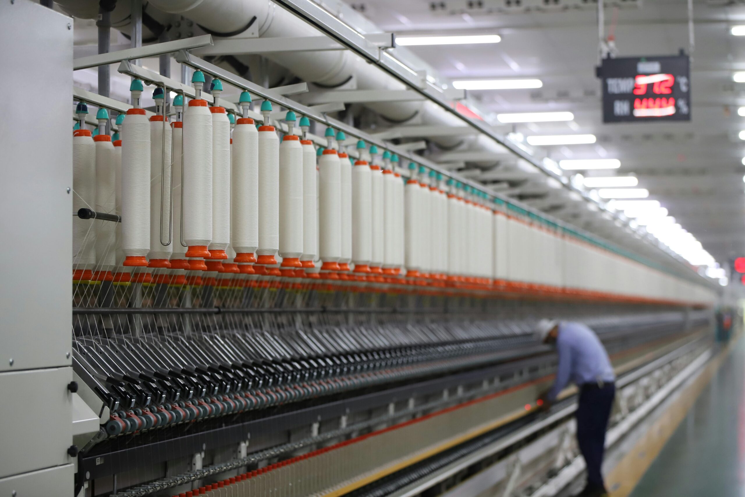 A textile factory in India showcasing modern spinning machinery with a worker.